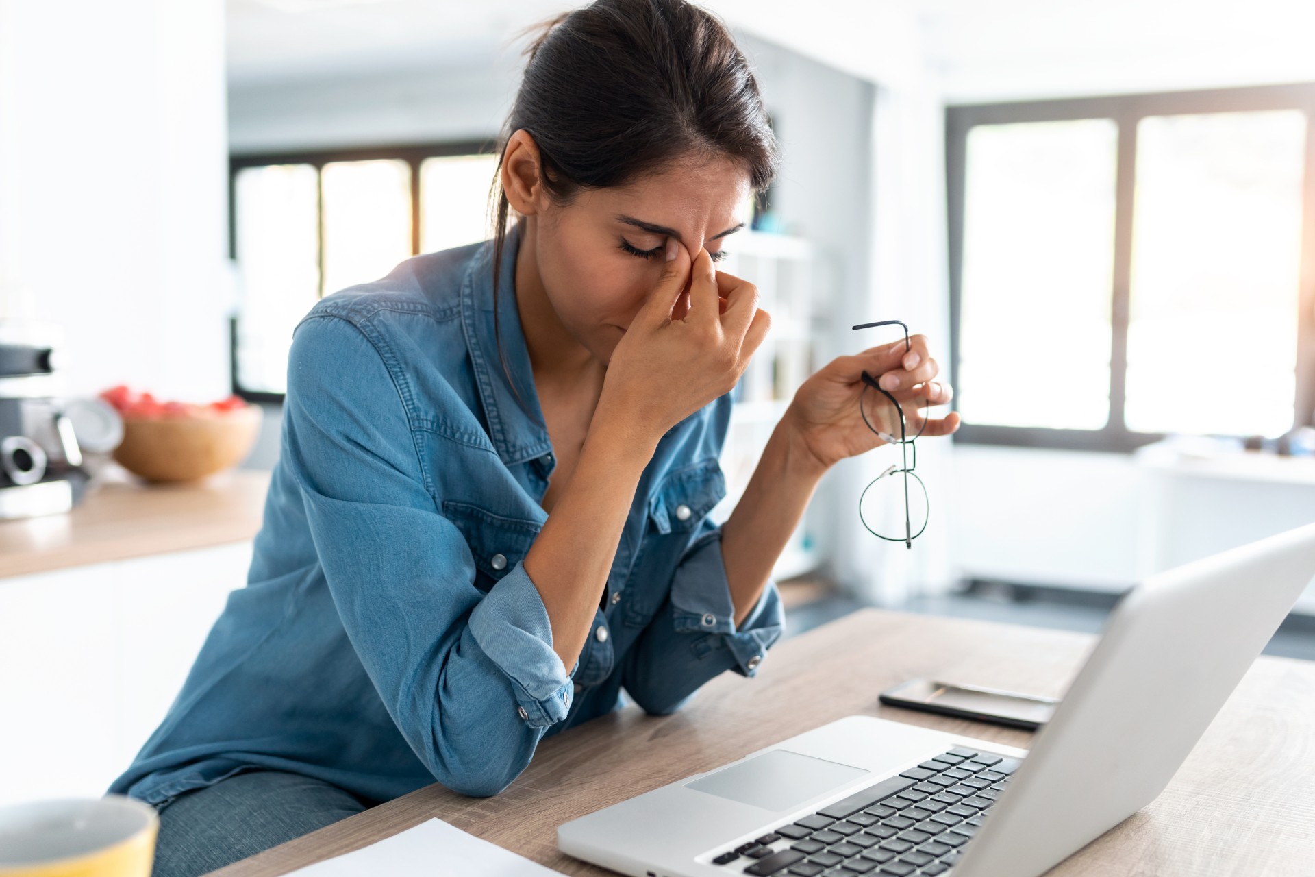 Stressed woman at desk fielding calls and emails